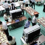 選挙区用には２台の自動読み取り機を使用。紙詰まりなどがあるとすぐ直せるよう、メーカーの職員も立ち会っている＝１０日夜、神戸市東灘区甲南町５