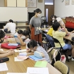高校生が子どもたちの勉強をサポートする西方寺での学習会。中央に立つのが発起人の吉野花さん＝７月下旬、神戸市東灘区御影本町６