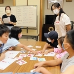 高校生たちが自作した英語かるたで遊ぶ子どもたち＝７月下旬、神戸市東灘区御影本町６