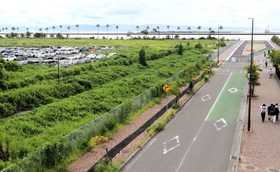 沿岸の眺望を生かし、グランピングなどの集客施設を公募することになった市有地（左）。駐車場で使われている区画とマリンパーク（奧）の間が今回の貸付対象地になる＝神戸市東灘区向洋町中９