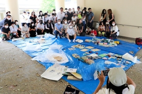 タイムカプセルの中身を広げて記念撮影する卒業生と元担任教諭たち＝神戸市東灘区住吉東町４