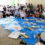 タイムカプセルの中身を広げて記念撮影する卒業生と元担任教諭たち＝神戸市東灘区住吉東町４