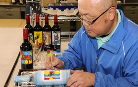 「光明兼光」の職人がイラストや模様を彫刻したボトル。１本ずつ手塗りしている＝姫路市飾磨区構