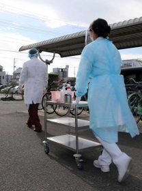 ＰＣＲ検査を実施している姫路市内の医療施設。防護服やフェースガードを着けた医師らが駐車場の車内で待つ患者の元へ向かう＝姫路市内