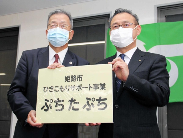 ４月上旬にあった事務所の開所式で、看板を受け取ったコムサロン２１の前川裕司理事長（左）＝姫路市呉服町