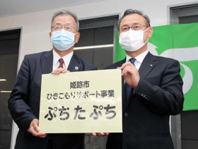 ４月上旬にあった事務所の開所式で、看板を受け取ったコムサロン２１の前川裕司理事長（左）＝姫路市呉服町