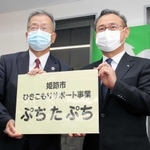 ４月上旬にあった事務所の開所式で、看板を受け取ったコムサロン２１の前川裕司理事長（左）＝姫路市呉服町