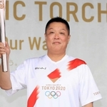 トーチを手に笑顔を見せる眞鍋政義さん＝姫路市本町
