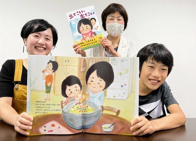 お気に入りのページを開く大和優月君といそのこつぶさん（左）ら＝姫路市内