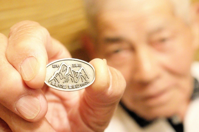 植田将志さんが売り歩く雪彦山のバッジ＝姫路市白銀町