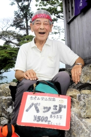 大天井岳山頂で一息つく植田将志さん。手製の看板に赤いバンダナがトレードマークだ＝姫路市夢前町山之内