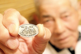 植田将志さんが売り歩く雪彦山のバッジ＝姫路市白銀町
