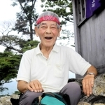 大天井岳山頂で一息つく植田将志さん。手製の看板に赤いバンダナがトレードマークだ＝姫路市夢前町山之内