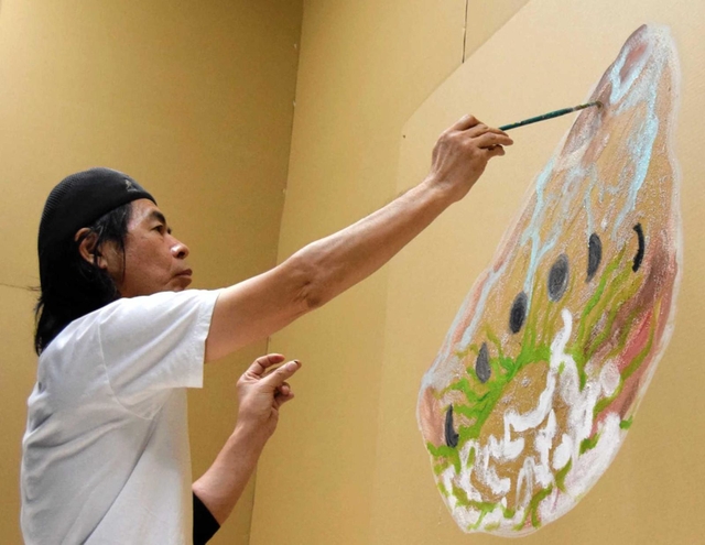 アサガオの種をモチーフに、会場入り口で作品を描く日比野さん＝姫路市立美術館