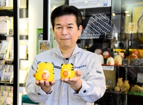 姫路独楽の技術を生かして作った「寅」のこけしを持つ村岡正樹さん＝姫路市南駅前町