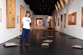 アレシンスキーと自身の作品が並ぶ会場で額縁にリードを付けて絵を移動させる日比野克彦さん＝姫路市立美術館
