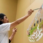 アサガオの種をモチーフに、会場入り口で作品を描く日比野さん＝姫路市立美術館