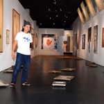 アレシンスキーと自身の作品が並ぶ会場で額縁にリードを付けて絵を移動させる日比野克彦さん＝姫路市立美術館