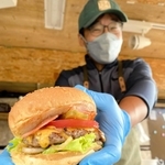 人気のベーコンチーズバーガー（７５０円）をアピールする光明寿さん＝姫路市飾東町山崎