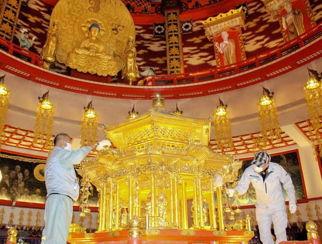 新年に向け、はたきで丁寧にほこりを落とす市職員ら＝名古山霊苑