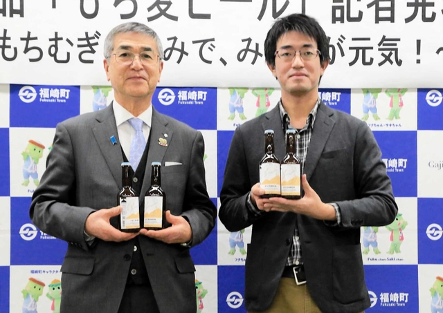福崎町産もち麦ビールをＰＲする六甲ビール醸造所の大渕拓也さん（右）と尾崎吉晴町長＝福崎町役場