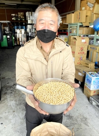 兵庫県産の大豆を手にする梅澤誠三社長＝姫路市飾磨区中島３