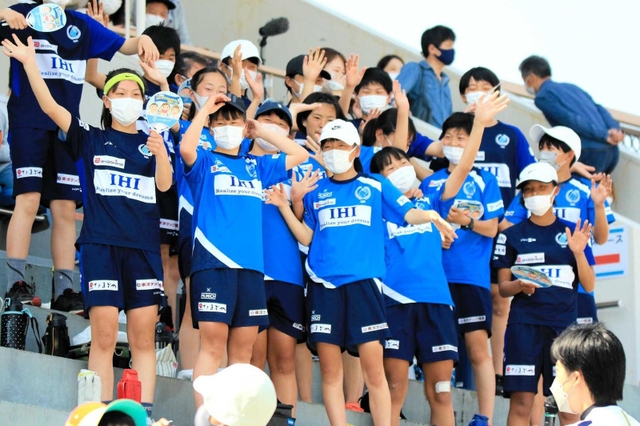 スタンドから声援を送るサッカー少女たち。ピッチを駆ける選手に自分の未来を重ねる＝１０日、ウインク陸上競技場