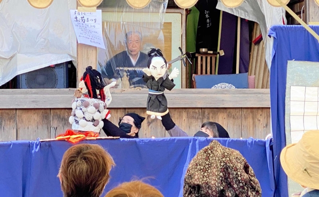 お菊が井戸から現れる場面を披露する人形劇＝十二所神社