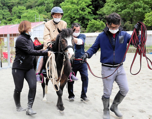 指導員が手綱を引くポニーにまたがり、乗馬を楽しむ高齢者＝姫路市夢前町山之内