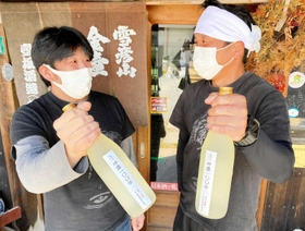 「呼應１００年」を手にする壺坂良昭さん（左）と飯塚祐樹さん（２０２２年５月）