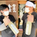 「呼應１００年」を手にする壺坂良昭さん（左）と飯塚祐樹さん（２０２２年５月）