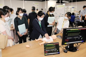 小児型のシミュレーターを使った心肺蘇生を見学する参加者ら＝県立大先端医療工学研究所