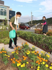ロータリーの花や芝生に水をやる地域住民たち＝姫路市相野