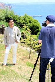 播磨灘を背景にミュージックビデオの撮影に臨んだみやま健二さん＝姫路市木場、小赤壁