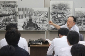 西二階町付近を走った機関車の写真パネルを見せながら、自身の経験などを語る黒田権大さん＝姫路市平和資料館