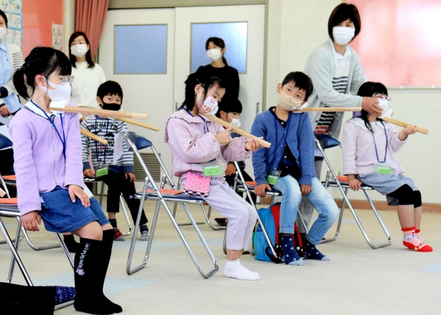 楽器の持ち方を学ぶ基礎練習。木の棒と発泡スチロールを組み合わせた道具をバイオリンに見立てる＝姫路市神子岡前３、面白山児童センター