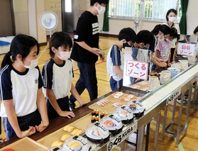 回転ずしの体験ゲームを通じ、食品ロス問題を学ぶ児童ら＝谷外小学校