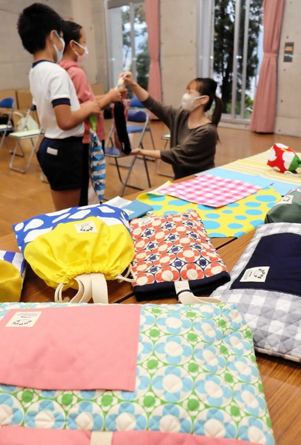 子ども向けの布製かばんや巾着袋などを受け取る児童たち＝姫路市広畑区蒲田