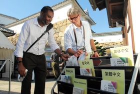 外国語のパンフレットを手にする観光客。外国人の姿が徐々に戻りつつある＝姫路市本町