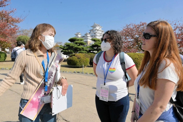 ガイドから姫路城の歴史を聞く外国人観光客＝姫路市本町