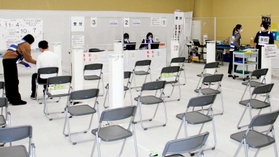 接種券などを確認する部屋は空席が目立つ。トラブルに対応する場所でもあり、ビブスを着たスタッフを多く配置している＝姫路市日出町３