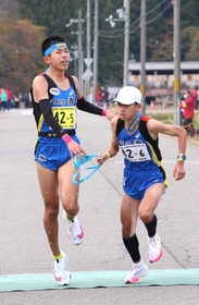 男子・姫路灘の５区田中壱基選手（左）からたすきを受け、駆け出す６区上田蒼大選手＝豊岡市日高町（撮影・長嶺麻子）