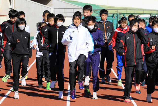田中希実選手（中央）のウオーミングアップを間近で見ながら体を動かす中高生ら＝姫路市中地