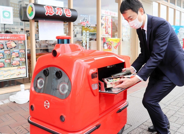 宅配ロボに商品を入れる福永力夫社長＝姫路市豆腐町