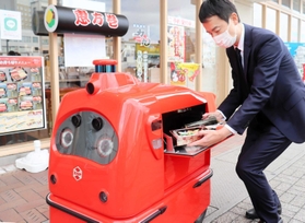 宅配ロボに商品を入れる福永力夫社長＝姫路市豆腐町