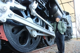 御立公園で保存されているＣ５７形を見上げる森澤康成さん。動輪は成人男性の背よりも大きい＝姫路市御立西４