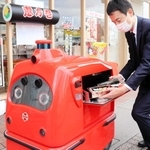 宅配ロボに商品を入れる福永力夫社長＝姫路市豆腐町