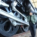 御立公園で保存されているＣ５７形を見上げる森澤康成さん。動輪は成人男性の背よりも大きい＝姫路市御立西４