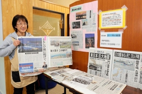 東日本大震災の津波被害などを伝える地方紙の切り抜きを並べる、養護教諭の中玉利展子さん＝高浜小学校