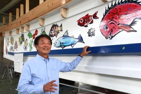 タイや松竹梅など縁起物が装飾された船の前に立つ奥村雅晴社長＝姫路市的形町的形